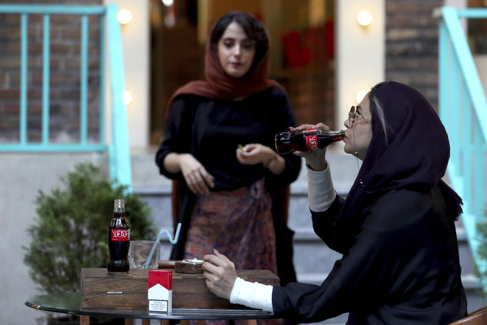 An Iranian drinks a Coca-Cola and smokes a Marlboro cigarette at a cafe in downtown Tehran, Iran, Wednesday, July 10, 2019. Whether at upscale restaurants or corner stores, American brands like Coca-Cola and Pepsi can be seen throughout Iran despite the heightened tensions between the two countries. U.S. sanctions have taken a heavy toll, but Western food, movies, music and clothing are still widely available. (AP Photo/Ebrahim Noroozi)