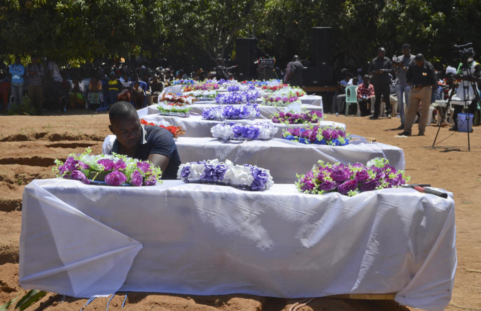Coffins for some of the victims of the capsized MV Nyerere passenger ferry are laid in a line during a mass burial ceremony on Ukara Island, Tanzania Sunday, Sept. 23, 2018. Burials started Sunday of the more than 200 people who died when the ferry capsized on Lake Victoria, while the country's Defense Minister said no further survivors were likely to be found and search efforts had ended. (AP Photo/Andrew Kasuku)