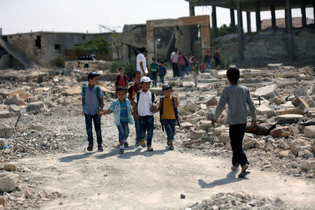 Pupils walk on debris in al-Saflaniyeh in eastern Aleppo's countryside, Syria September 17, 2017. REUTERS/Khalil Ashawi