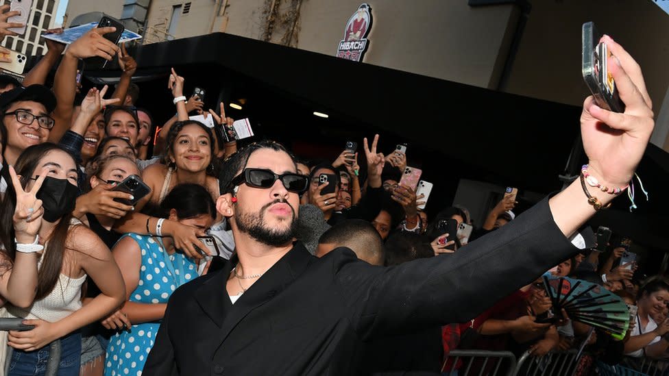 Bad Bunny se toma una selfie con fanáticos que están detrás de una valla en Los Ángeles en agosto de 2022.