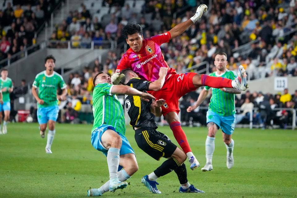 Seattle forward Jordan Morris (left) collides into Crew midfielder Sean Zawadzki and goaltender Abraham Romero on Saturday.