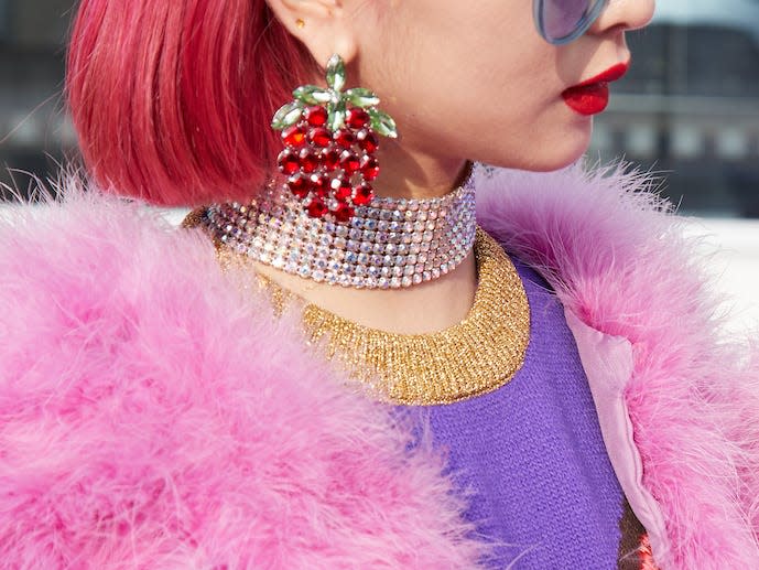 two women with pink hair wearing matching outfits with big jewelry and pink fuzzy coats