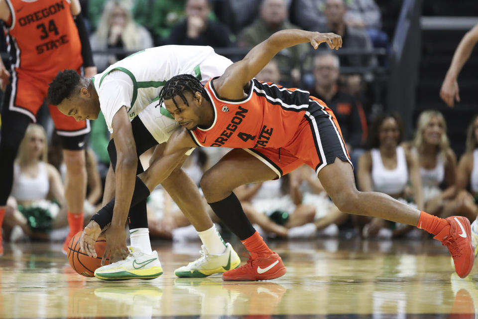 Oregon forward Kwame Evans Jr., left, and Oregon State guard Dexter Akanno scramble for the ball during the first half of an NCAA college basketball game Wednesday, Feb. 28, 2024, in Eugene, Ore. (AP Photo/Amanda Loman)