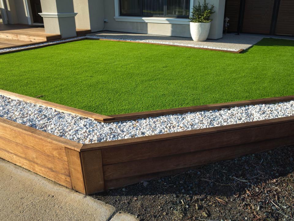 Artificial grass lawn turf with wooden edging in the front yard of a modern Australian home or residential house.