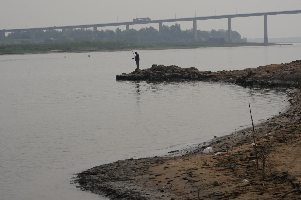 A man fishes on the shore of the Paraguay River in Mariano R. Alonso, Paraguay, Monday, Sept. 9, 2024. Water levels have plunged to their lowest-ever level amid a drought, according to Paraguay's Meteorology and Hydrology Office. (AP Photo/Jorge Saenz)