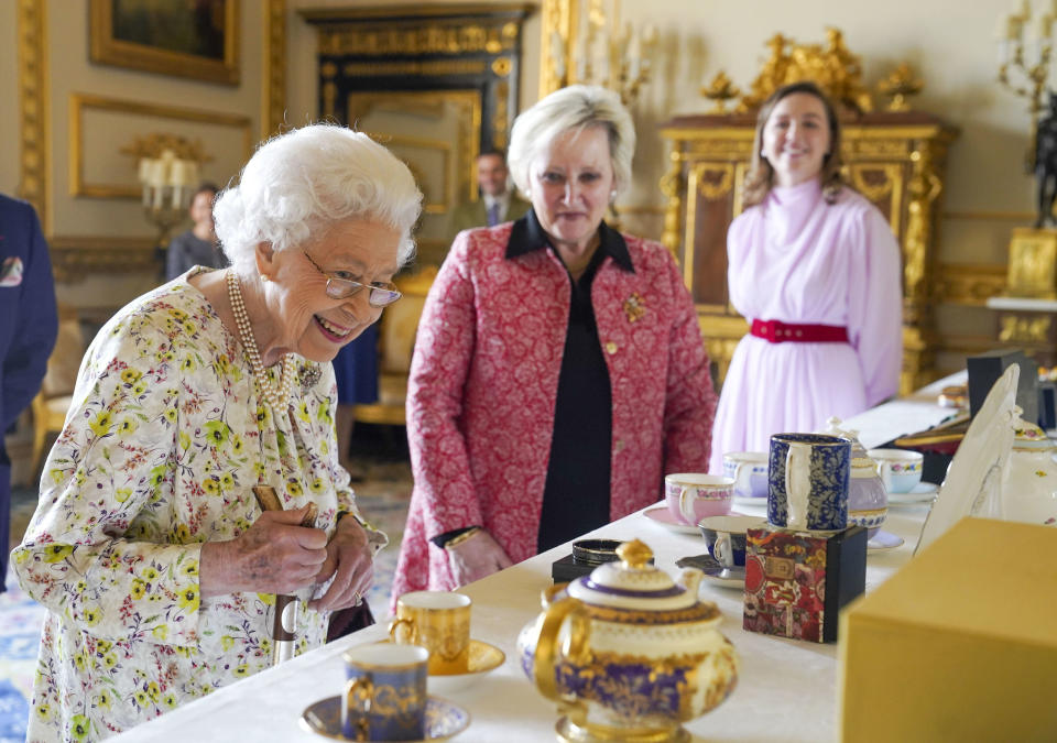 <p>The Queen talks to Pamela Harper, centre, from British craftwork company, Halcyon Days as she views a display of artefacts to commemorate the company's 70th anniversary in the White Drawing Room at Windsor Castle on 23 March 2022.</p> 