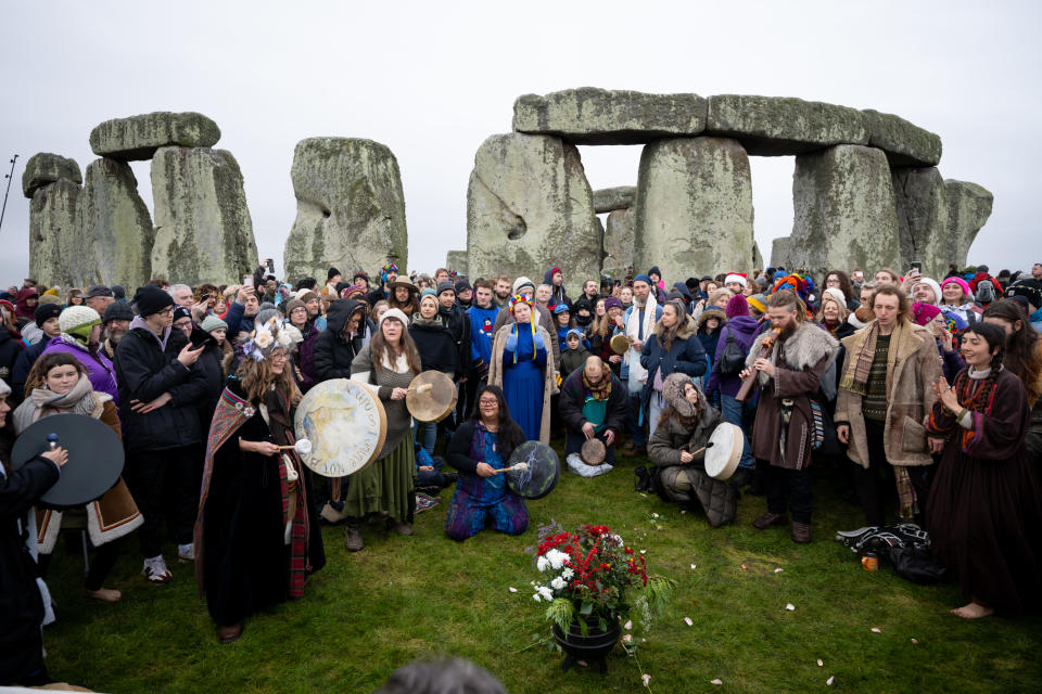 AMESBURY, ENGLAND - DECEMBER 22: People greet the sunrise at Stonehenge, on December 22, 2022, in Amesbury, United Kingdom. The famous historic stone circle, a UNESCO listed ancient monument and World Heritage Site, attracts visitors to celebrate the sunrise closest to the Winter Solstice, the shortest day of the year. The event is claimed to be more important in the pagan calendar than the summer solstice, because it marks the 're-birth' of the Sun for the New Year. (Photo by Finnbarr Webster/Getty Images)