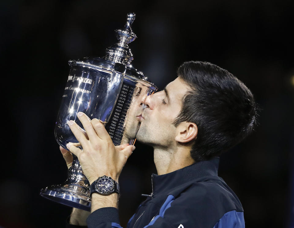 FILE - In this Sept. 9, 2018, file photo, Novak Djokovic, of Serbia, kisses the trophy after defeating Juan Martin del Potro, of Argentina, in the men's final of the U.S. Open tennis tournament, in New York. Djokovic announced Thursday, Aug. 13, 2020, he will enter the Grand Slam tournament and the hard-court tuneup preceding it in New York. (AP Photo/Adam Hunger, File)