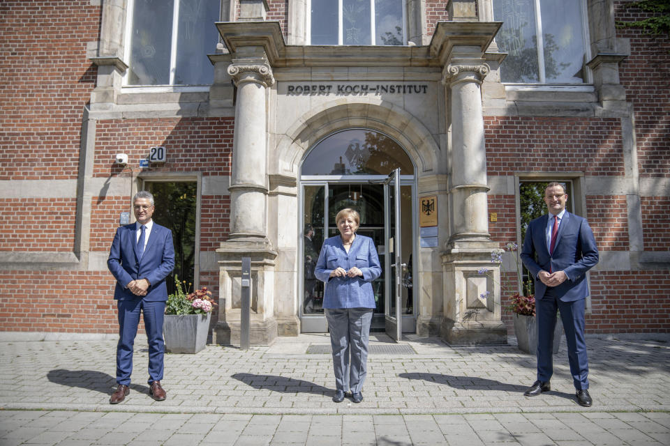 German Chancellor Angela Merkel, center, stands next to Jens Spahn, Federal Minister of Health, and Lothar Wieler, President of the Robert Koch Institute (RKI), left, for a picture in front of the entrance to the RKI in Berlin, Germany, Tuesday, July 13, 2021. Merkel visited the health ministry's leading institute in the Corona pandemic at the invitation of Health Minister Spahn. (Michael Kappeler/Pool via AP)