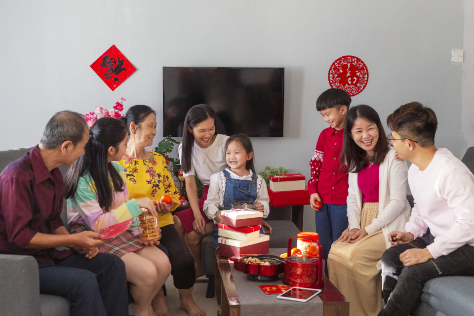 Three generation Chinese family reunion in living room during Chinese New Year, gathering, talking and eating snacks