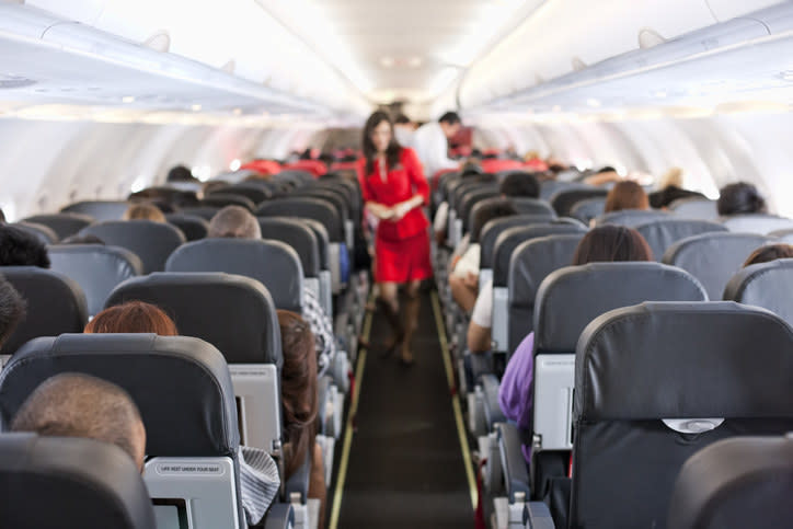 A flight attendant in the aisle of an airplane
