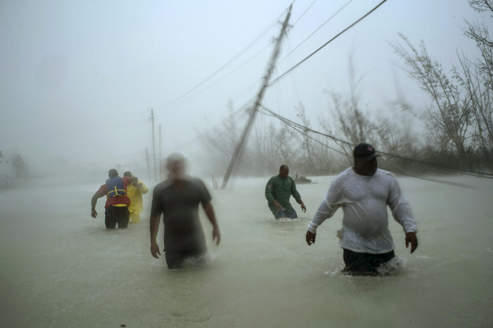 Volunteers wade through a flooded road against wind and rain caused by Hurricane Dorian to rescue families near the Causarina bridge in Freeport, Grand Bahama, Bahamas, Tuesday, Sept. 3, 2019. The storm's punishing winds and muddy brown floodwaters devastated thousands of homes, crippled hospitals and trapped people in attics. (AP Photo/Ramon Espinosa)