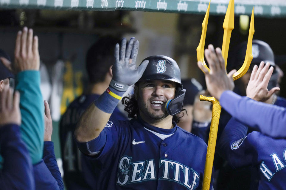 FILE - Seattle Mariners' Eugenio Suárez, holds a trident, as he's greeted in the dugout after after hitting a three-run home run against the Oakland Athletics in Oakland, Calif., Wednesday, May 3, 2023. About half the clubs in MLB are using some kind of prop or ritual to celebrate a big hit or a big play in ways that often go viral. (AP Photo/Godofredo A. Vásquez, File)