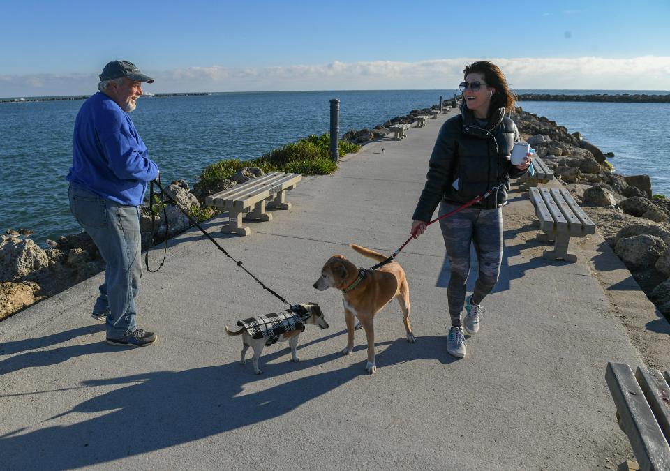 Mike Giz (left), of Fort Pierce, and Ivy Robinson, of Charlotte, North Carolina and Fort Pierce, cross paths while both were out for walks with their dogs along the Fort Pierce south jetty in the coldest weather of the winter season on Monday, Jan. 24, 2022, in Fort Pierce. "The crazy weather, it's a little chilly," Robinson said. The morning low temperature at the jetty was in the upper 30s by sunrise warming up to the low 60s. 