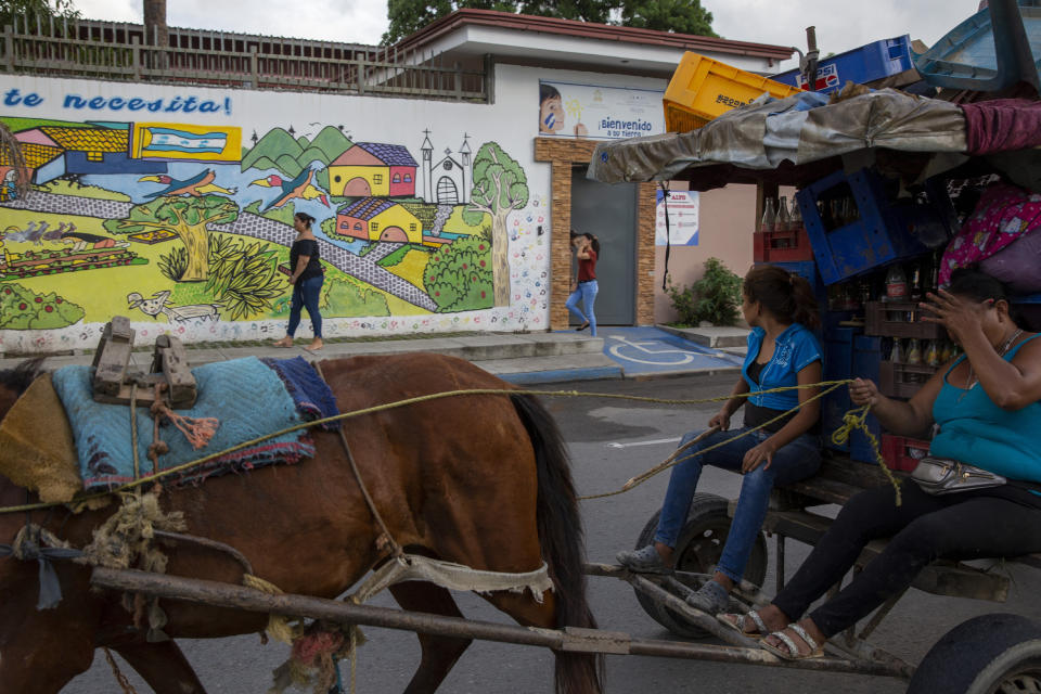 A woman stands at the main entrance of the Belen migrant care center waiting for information on her relatives, in the Medina neighborhood of San Pedro Sula, Honduras, on Nov. 29, 2019. (AP Photo/Moises Castillo)