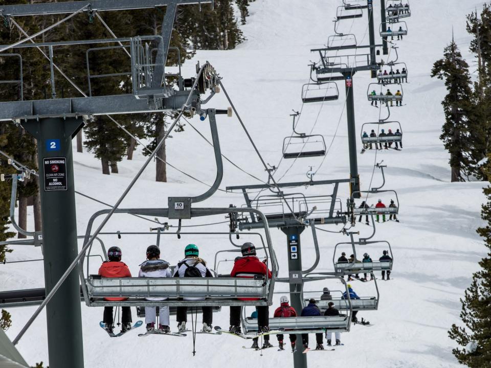 Skiers on chairlift heading up snow-covered mountain in Lake Tahoe