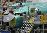 FILE - In this March 27, 2019, file photo, a worker enters a Boeing 737 MAX 8 airplane during a brief media tour of Boeing's 737 assembly facility in Renton, Wash. On Monday, Dec. 16, shares of Boeing are falling before the opening bell on a report that the company may cut production of its troubled 737 Max or even end production all together. (AP Photo/Ted S. Warren, File)