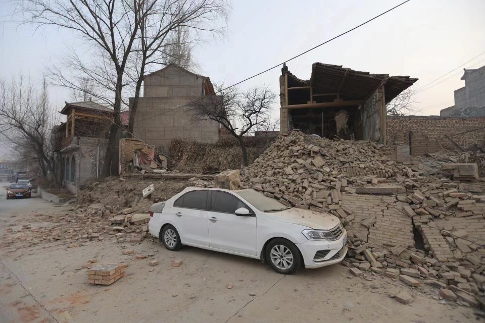 A vehicle is partially covered by a collapsed building in the aftermath of an earthquake in Dahejia village of Jishishan county in northwestern China's Gansu province Tuesday, Dec. 19, 2023. An overnight earthquake killed multiple people in a cold and mountainous region in northwestern China, the country's state media reported Tuesday.(Chinatopix via AP)