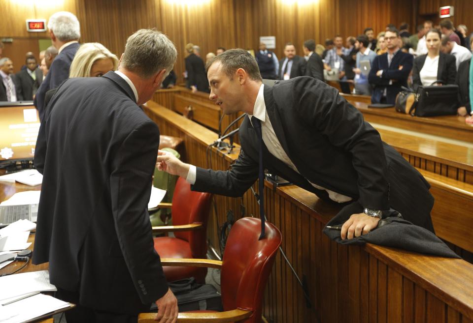 Oscar Pistorius, speaks to his lawyers while in the dock on the second day of his trial at the high court in Pretoria, South Africa, Tuesday, March 4, 2014, talks with members of his defense team during a break in proceedings. Pistorius is charged with murder for the shooting death of his girlfriend, Reeva Steenkamp, on Valentines Day in 2013. (AP Photo/Kim Ludbrook, Pool)