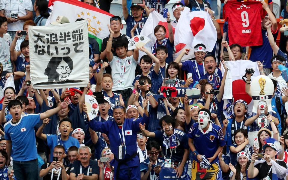 Japanese fans celebrate their 2-1 victory over Colombia - before halting the celebrations to clean up the stands  - REUTERS