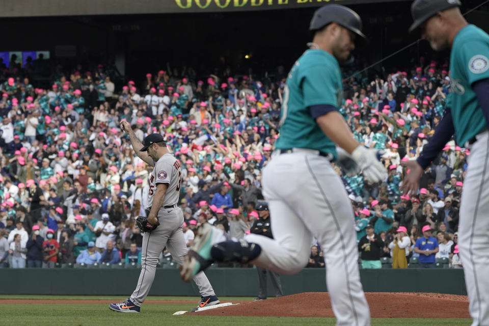 Houston Astros starting pitcher Justin Verlander, left, walks near the mound as Seattle Mariners' Ty France, center, is greeted by third base coach Manny Acta, right, after France hit a solo home run during the third inning of a baseball game Friday, May 27, 2022, in Seattle. (AP Photo/Ted S. Warren)