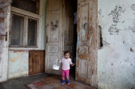 Fruzsina, a Hungarian Roma girl, exits her family's home in Bodvaszilas, Hungary, Monday, April 12,2021. Many students from Hungary's Roma minority do not have access to computers or the internet and are struggling to keep up with online education during the pandemic. Surveys show that less than half of Roma families in Hungary have cable and mobile internet and 13% have no internet at all. (AP Photo/Laszlo Balogh)