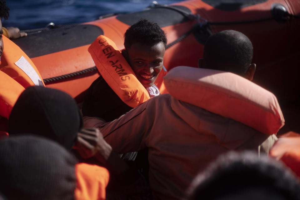 A migrant smiles as he is assisted with others by aid workers of the Spanish NGO Open Arms, after fleeing Libya on board a precarious wooden boat in the Mediterranean sea, about 110 miles north of Libya, on Saturday, Jan. 2, 2021. (AP Photo/Joan Mateu)