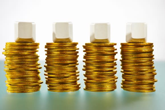 Four stacks of gold coins with blank white blocks on top of them