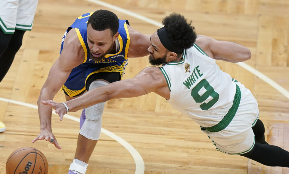 Boston Celtics guard Derrick White (9) and Golden State Warriors guard Stephen Curry (30) scramble for a loose ball during the first quarter of Game 6 of basketball's NBA Finals, Thursday, June 16, 2022, in Boston. (AP Photo/Steven Senne)