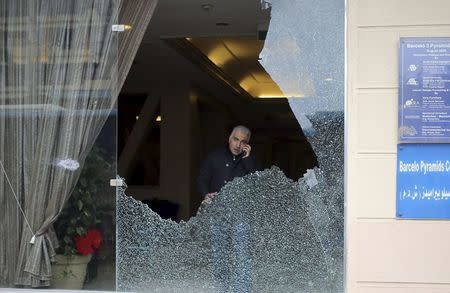 A police investigator is seen through a smashed window at a hotel where gunmen attacked tourists in front of a hotel in Giza, Greater Cairo, Egypt January 7, 2016. REUTERS/Asmaa Waguih