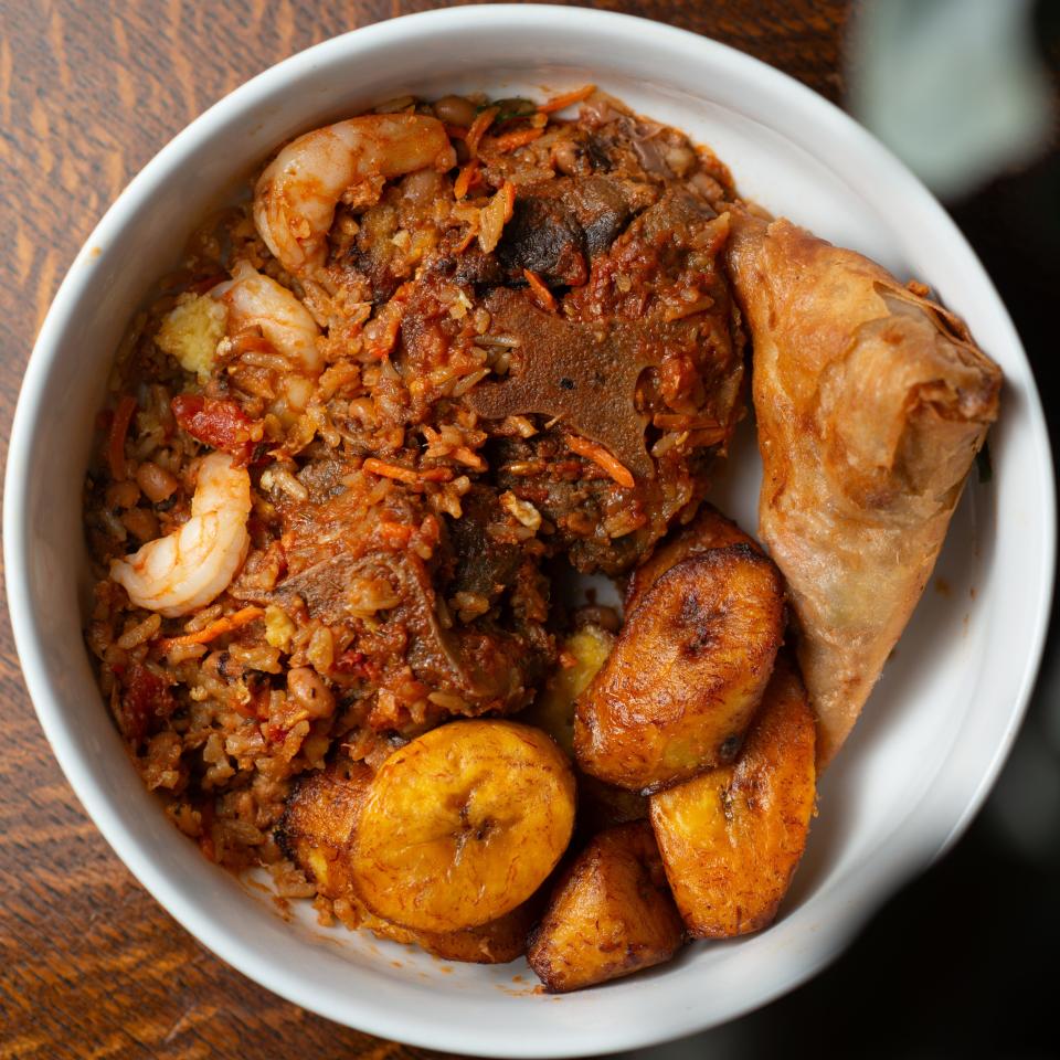 A samplings of food from KononiaTouch African Cuisine features a shrimp fried rice, plantains, ox tail, rice, beans and a samosa fried pastry.