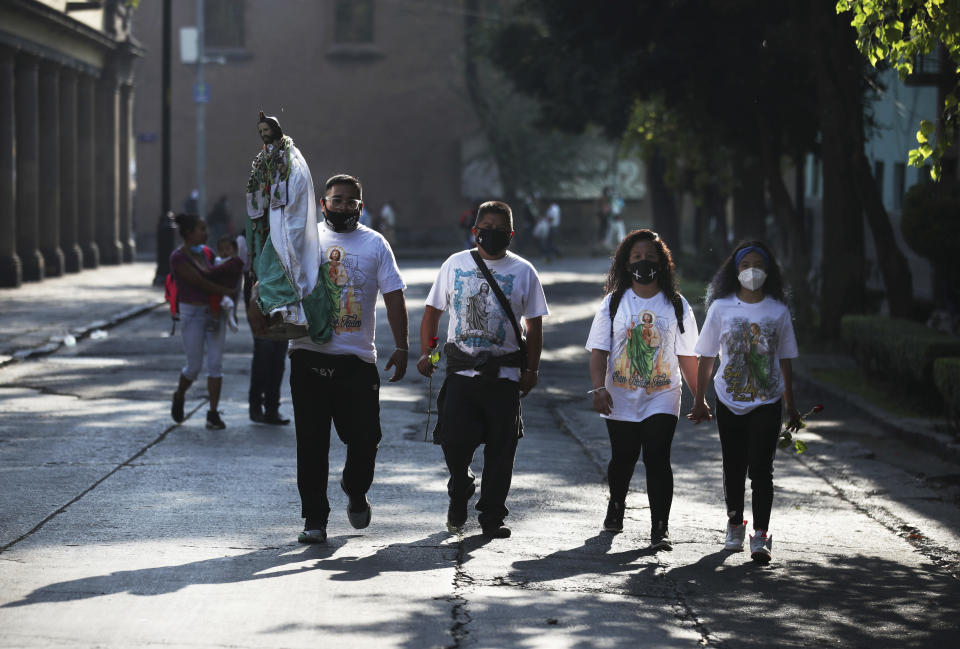 Devotees, wearing protective face masks amid the new coronavirus pandemic, arrive to the San Hipolito Catholic church during the annual pilgrimage honoring Saint Jude, the patron saint of lost causes, in Mexico City, Wednesday, Oct. 28, 2020. Thousands of Mexicans did not miss this year to mark St. Jude's feast day, but the pandemic caused Masses to be canceled and the rivers of people of other years were replaced by orderly lines of masked worshipers waiting their turn for a blessing. (AP Photo/Marco Ugarte)