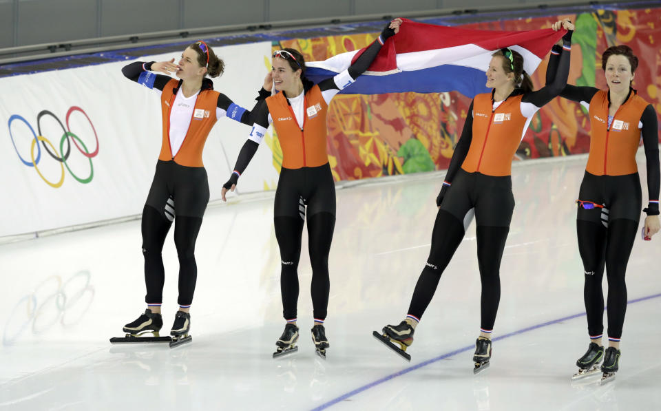 Athletes from the Netherlands, left to right, Ireen Wust, Marrit Leenstra, Lotte van Beek and Jorien ter Mors hold their national flag and celebrate their gold in the women's team pursuit at the Adler Arena Skating Center at the 2014 Winter Olympics, Saturday, Feb. 22, 2014, in Sochi, Russia. (AP Photo/Matt Dunham)