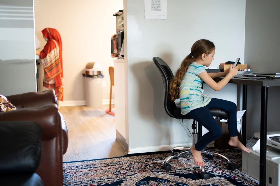 Aman Mashwani, 5, plays on her fathers phone as her mother, Salma, makes dinner on Aug. 28. Wednesday marks two years since the U.S. withdrew from Afghanistan.