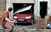 Un homme sur un vélo passe devant un garage détruit par les intempéries. AFP