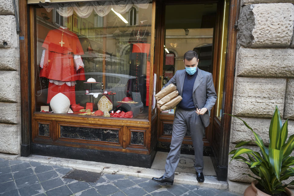 A shop attendant walks out of the Gammarelli clerical clothing shop, in Rome, Thursday, Nov. 26, 2020. The consistory to elevate new cardinals scheduled for Saturday, Nov. 28, in the time of coronavirus is like nothing the Holy See has ever seen. A handful of soon-to-be cardinals are in protective coronavirus quarantine, including African-American, Cardinal-designate Wilton Gregory, archbishop of Washington who explained that a U.S.-based ecclesiastical tailor took his measurements while he was still in Washington and sent them to Gammarelli, which then made them to order and sent them to Santa Marta hotel where he is undergoing the quarantine. (AP Photo/Andrew Medichini)