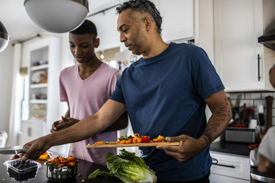 Father and teenage son cooking together in kitchen, getting back on track after the holidays