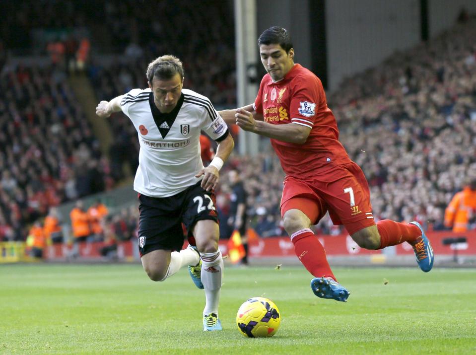 Liverpool's Luis Suarez (R) challenges Fulham's Elsad Zverotic during their English Premier League soccer match at Anfield in Liverpool, northern England November 9, 2013.