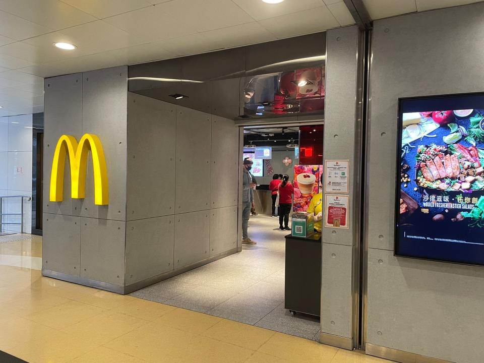 The exterior of McDonald's Next with McDonald's logo on outside on a gray industrial wall and a entryway to restaurant