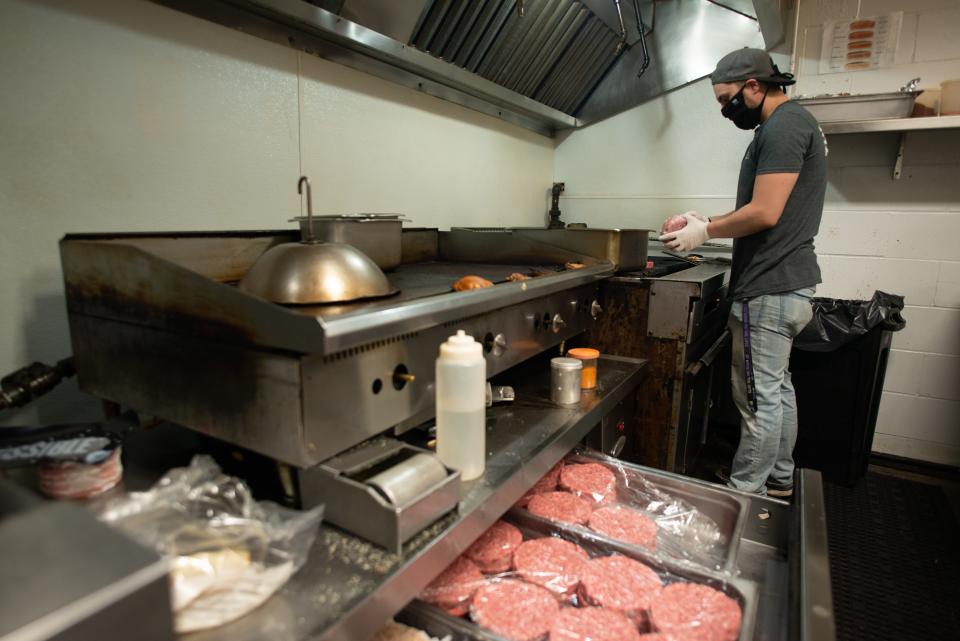 Garrett Taylor, a cook at The Burger Stand, 2833 S.W. 29th St., tosses burger patties on the grill for customers custom burger orders on May 5, 2021.