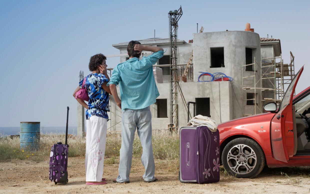 Couple in front of half built villa. Credit: Peter Cade/Getty Images