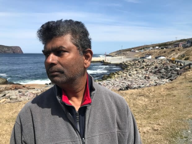 Don Jayasinghe stands near a search and rescue operation on Thursday afternoon in Flatrock, N.L., a day after his son, Supul, slipped on rocks near the water and fell in. (Terry Roberts/CBC - image credit)