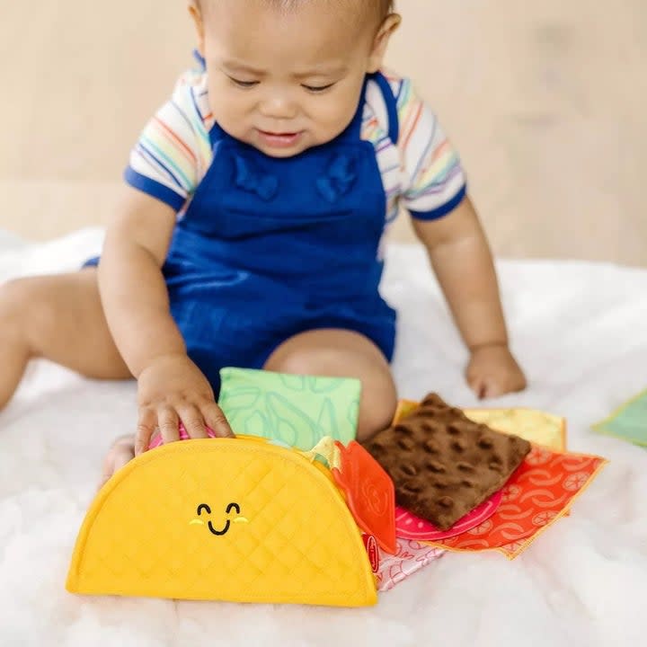 Baby model playing with happy-faced taco toy