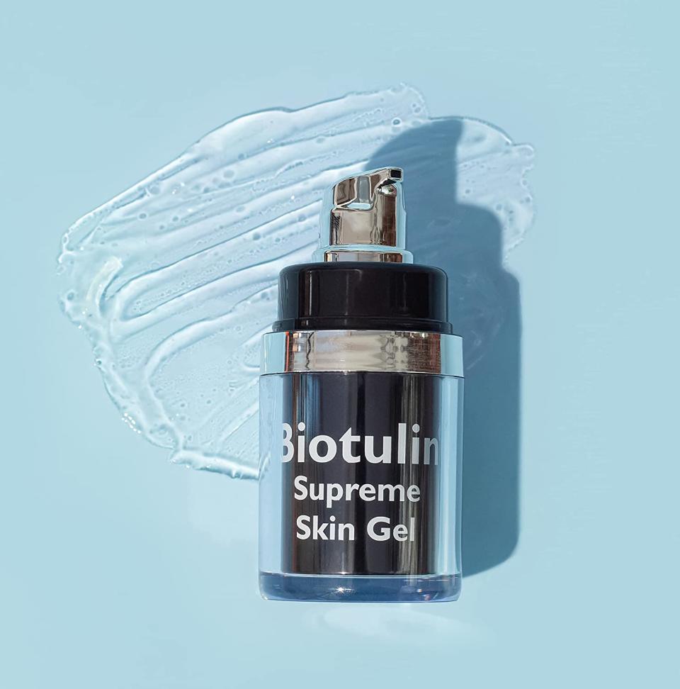 A bottle of Biotulin Supreme Skin Gel is shown on a blue background with some of the gel smeared behind it.