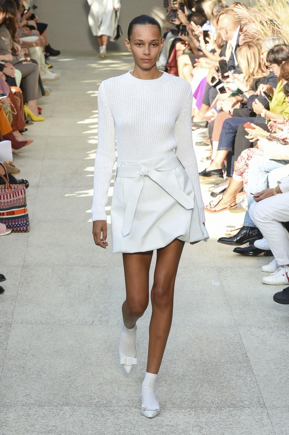 Model Binx Walton on the runway at Salvatore Ferragamo spring ’20 in a pair of white Vara flats and white socks. - Credit: Shutterstock