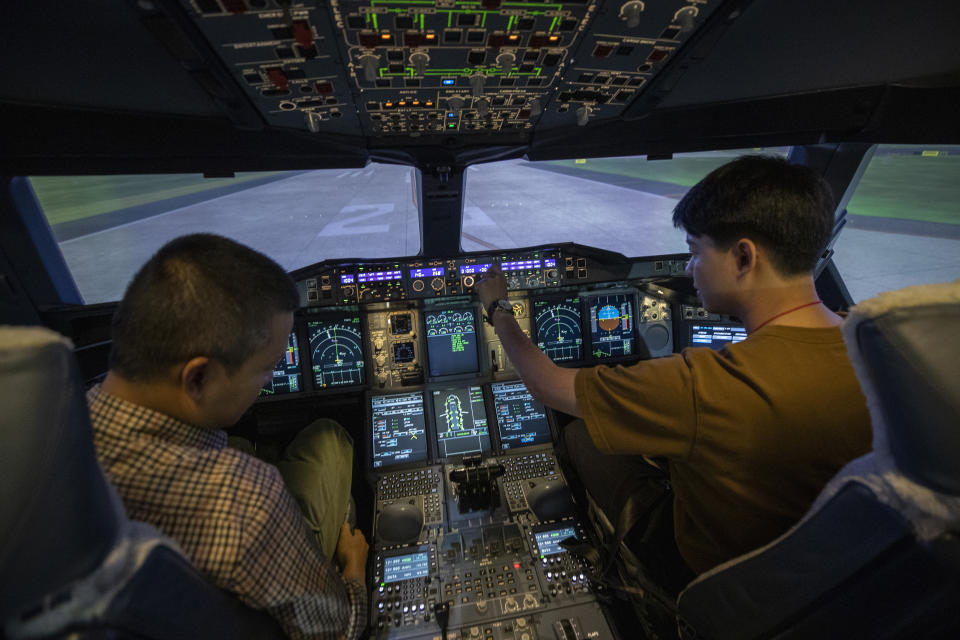 Customers sit in a Boeing A380 flight simulator during a flight experience at the Thai Airways head office in Bangkok, Thailand on Oct. 3, 2020. The airline is selling time on its flight simulators to wannabe pilots while its catering division is serving meals in a flight-themed restaurant complete with airline seats and attentive cabin crew. The airline is trying to boost staff morale, polish its image and bring in a few pennies, even as it juggles preparing to resume international flights while devising a business reorganization plan. (AP Photo/Sakchai Lalit)