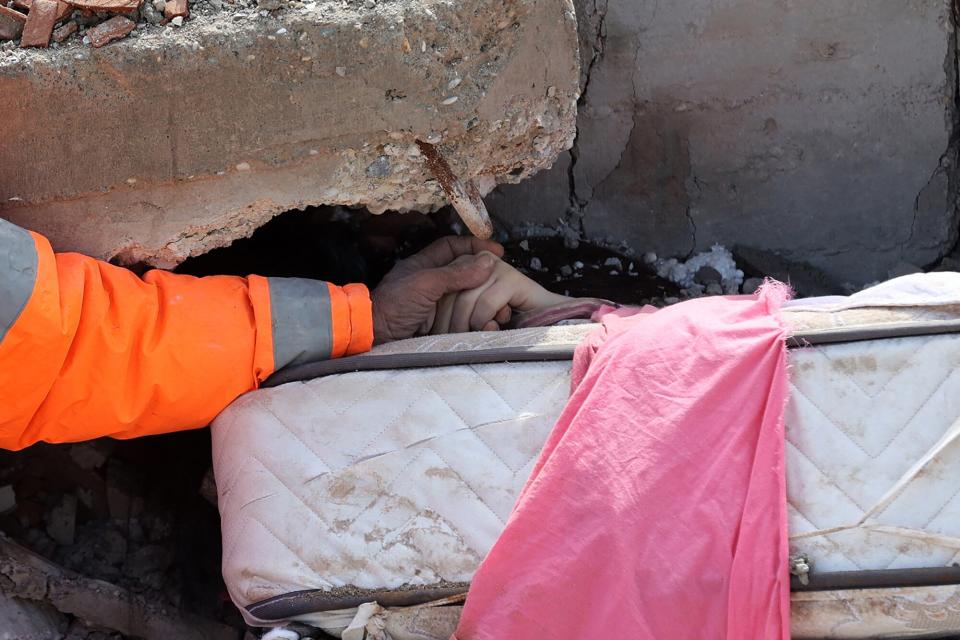 Mesut Hancer holds the hand of his 15-year-old daughter Irmak, who died in the earthquake in Kahramanmaras, close to the quake's epicentre, the day after a 7.8-magnitude earthquake struck the country's southeast, on February 7, 2023. - Rescuers in Turkey and Syria braved frigid weather, aftershocks and collapsing buildings, as they dug for survivors buried by an earthquake that killed more than 5,000 people. Some of the heaviest devastation occurred near the quake's epicentre between Kahramanmaras and Gaziantep, a city of two million where entire blocks now lie in ruins under gathering snow.