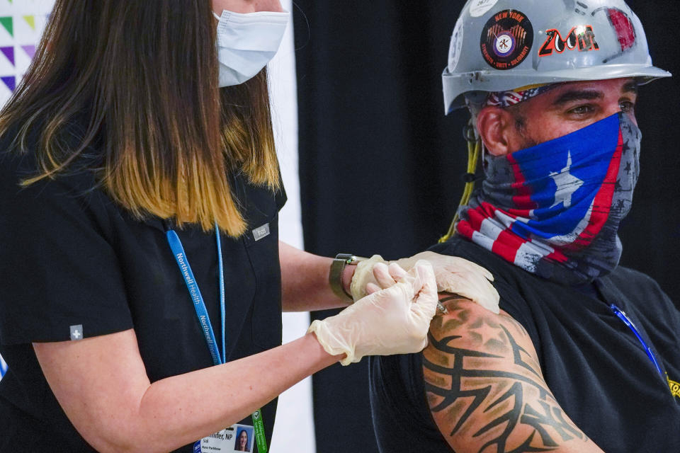 FILE - In this April 14, 2021 file photo, a Northwell Health nurse injects Local 28 Sheet Metal Worker Demetrius Buttelman with the first dose of the Pfizer vaccine during a news conference, at the Belmont Park in Elmont, N.Y. The state recorded 43,000 new cases in the week that ended Saturday, April 17, 2021. That's the lowest number in a seven-day period since Thanksgiving. (AP Photo/Mary Altaffer, Pool, File)