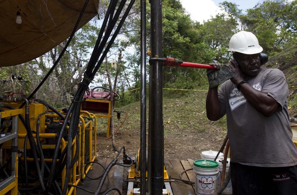 In this picture taken on April 10, 2012, a drill worker listens for the bit, hundreds of feet underground, during exploratory drilling for minerals and metals in the mountains in the department of Trou Du Nord, Haiti. Haiti's land may yet hold the solution to centuries of poverty: there is gold hidden in its hills, and silver and copper too. Now, two mining companies are drilling around the clock to determine how to get those metals out, and how much it might cost.  (AP Photo/Dieu Nalio Chery)