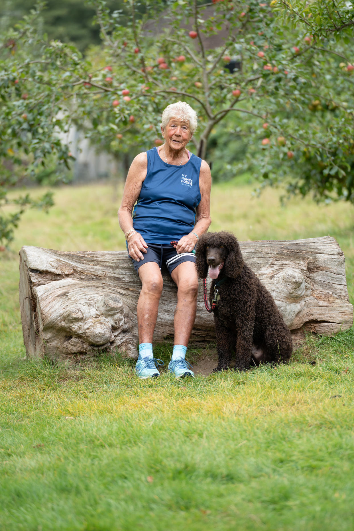 Caroline Quibell sitting on a tree trunk with her dog Streak